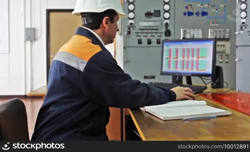 Engineer works on computer sitting at desk, close-up