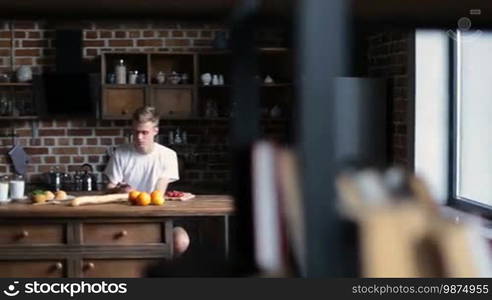 Enjoying a nice morning together. Positive young couple bonding with each other and smiling while having breakfast in the kitchen. Sweetheart couple kissing and communicating in the morning while sharing breakfast.