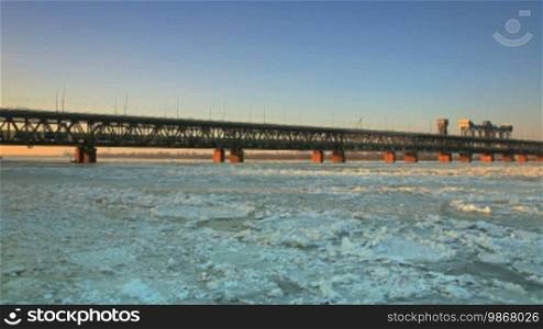 Evening time lapse. Railway bridge with ice floes.