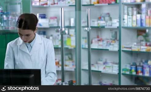 Experienced female pharmacist standing behind the counter and counseling customer in drugstore closeup. Smiling chemist woman druggist suggesting medical drug to patient in pharmacy. Health care and pharmacology concept.