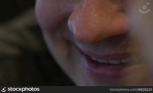 Extreme close-up of a young smiling man. At first focus on his mouth then on the eyes