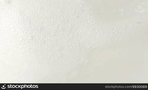 Extreme macro detail of clear soda pouring into glass with ice