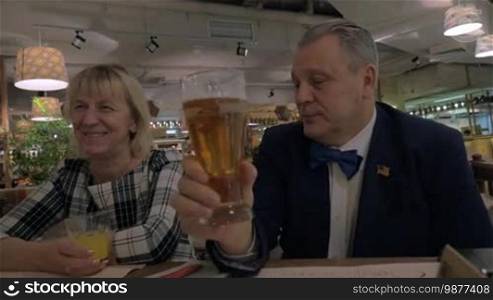 Family members clanging glasses of beer and juice during celebratory dinner in the restaurant. Man wearing US flag badge