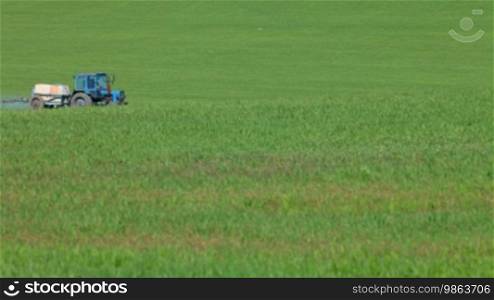 Farming tractor spraying a field