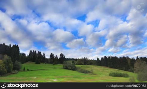 Fast cloud movement above green hill and forest, timelapse