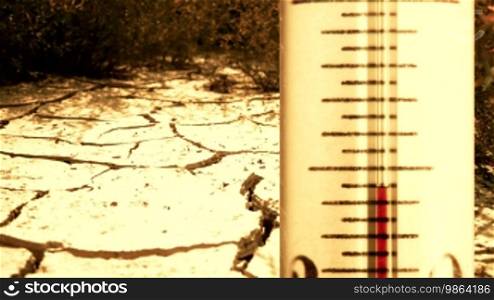 Fast rising temperature on the thermometer, large cracks in the ground during the dry season in the background