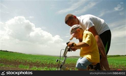 Father helping child learn to ride a bike