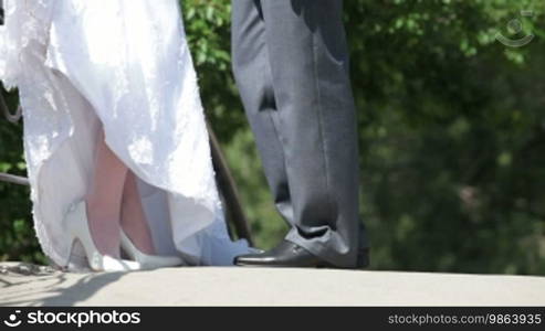 Feet of bride and groom standing, hugging on bridge