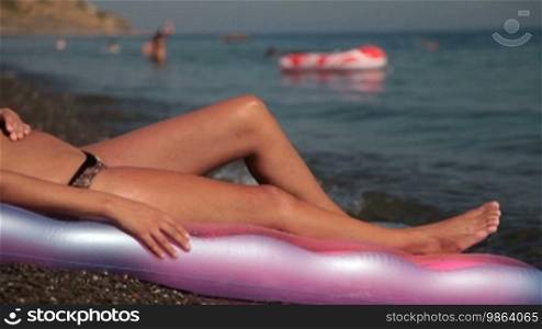 Feet of young woman sunbathing on the beach
