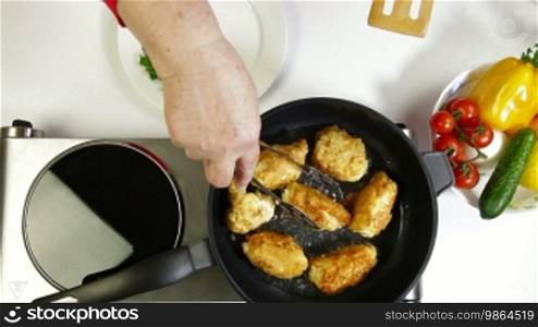 Female frying chicken breast roll on a pan. Shot from above