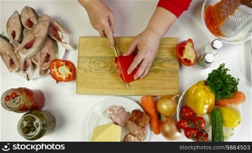 Female hands cooking ingredients for baked fish - chopping bell pepper. Shoot from above