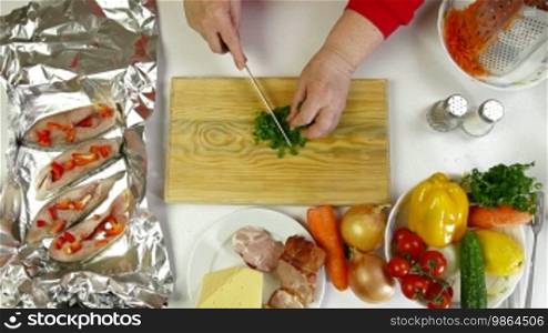 Female hands cooking ingredients for baked fish - chopping parsley
