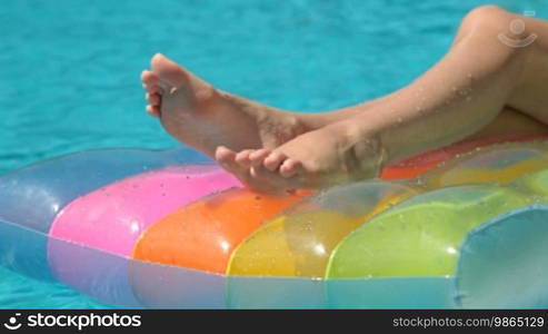 Female legs on pool raft in swimming pool