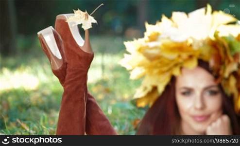 Female legs wearing high heel stiletto boots and autumn leaf