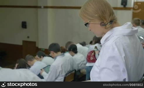 Female medical student using a tablet computer in a lecture at the university or conference, then turning to the camera and smiling