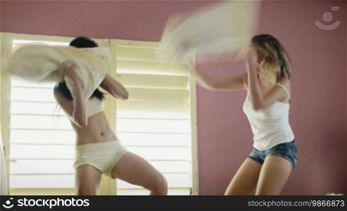 Female teens fighting with pillows in bedroom