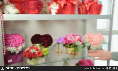 Florist serving customer in flower shop, man buying rose basket arrangement, closeup, focus on the bouquet
