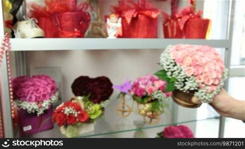 Florist serving customer in flower shop, man buying rose basket arrangement, closeup, focus on the bouquet
