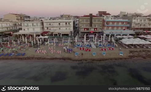 Flying along the sea shore with hotels and empty chaise-longues in the evening. Resort in Thessaloniki, Greece