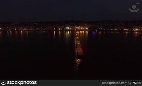 Flying from the pier with people to the coast with resort. Night scene in Thessaloniki, Greece