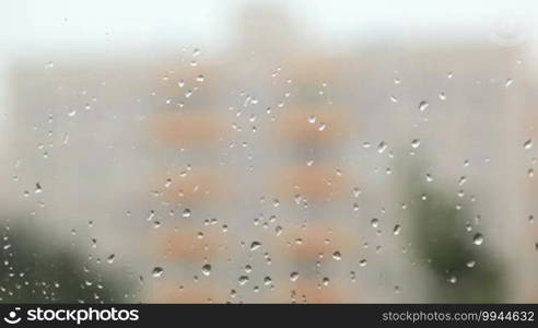 Focus pulling from glass with rain drops to the building.