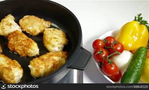 Frying chicken breast roll on a pan.