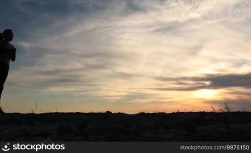 Full length of slim fitness woman with perfect body running on the beach against colorful cloudy sky in glow of beautiful sunset. Sporty female runner with ponytail jogging on seaside at sunset. Slow motion. Steadicam stabilized shot.