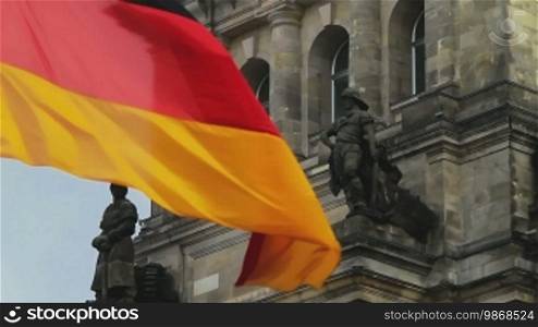 German flag waving in front of Parliament building in Berlin. Roof of the building in Berlin, close up.