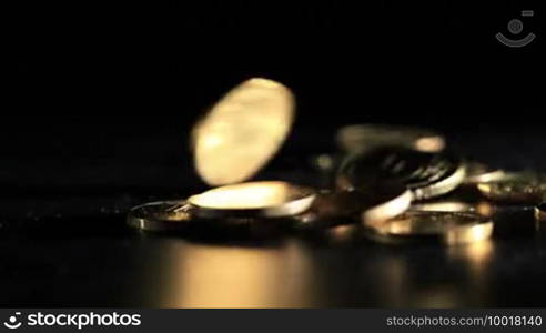 Gold coins falling over dark background. Macro shot.