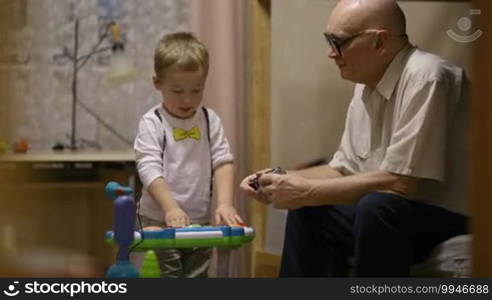 Grandfather sitting and watching two little boys playing.