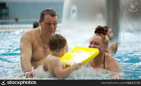 Grandparents watching their grandson having fun in the swimming pool