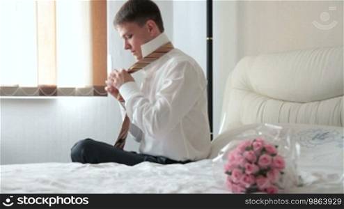 Groom tying his tie preparing for the wedding ceremony