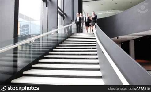 Group of business people walking and talking at stairs in an office building