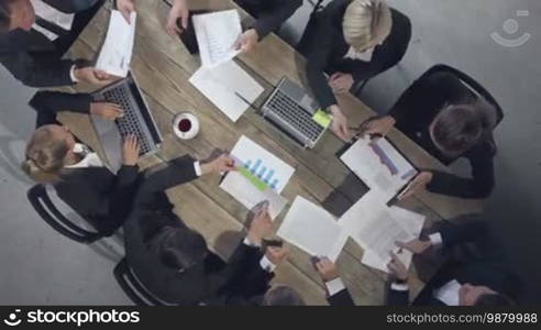 Group of diverse business executives holding a meeting around a table discussing graphs charts showing statistical data analysis