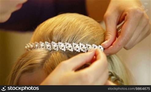 Hairdresser pinning up bride's tiara before the wedding