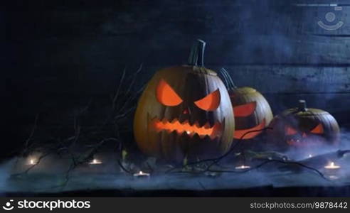 Halloween pumpkins, jack-o'-lantern, and candles in blue light and mist
