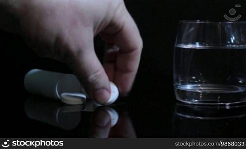 Hand of man throws an aspirin into a glass of water. Video shot slider DITOGEAR.