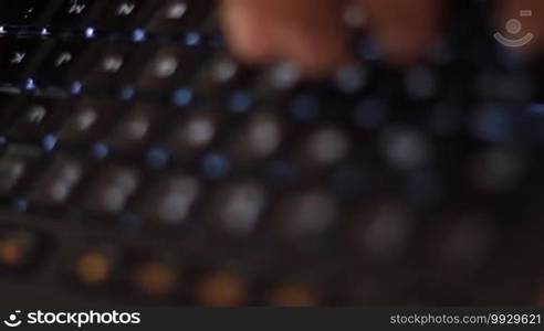 Hands of a man entering data into a modern illuminated keyboard