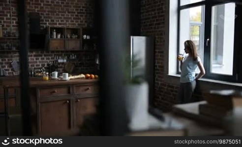 Handsome young man inviting his beautiful girlfriend to dance in modern kitchen. Romantic couple in love dancing slow dance, enjoying nice morning together in the kitchen. Slow motion. Steadicam stabilized shot.