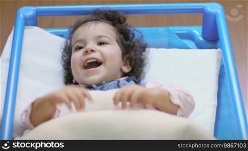 Happy baby girl in cot at school