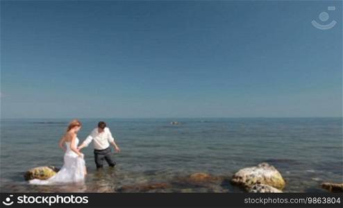 Happy bride and groom are laughing by the sea
