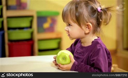 Happy children and healthy food, female child eating green apple in kindergarten. Sequence