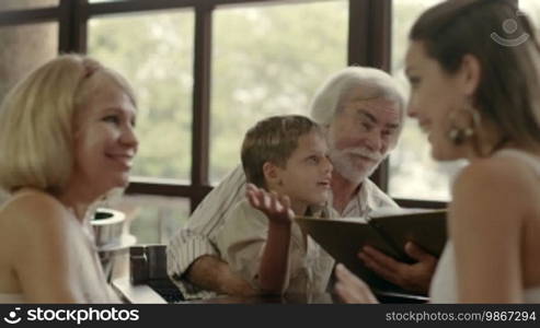 Happy family with husband, wife, child, grandfather, and grandmother choosing food and drinks in a bar