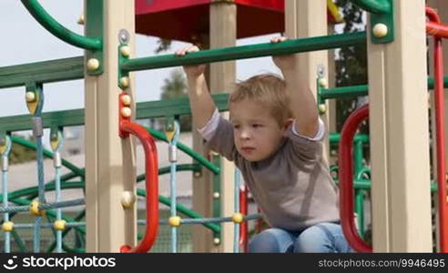 Happy little boy having fun on playground equipment and then something attracts his attention.