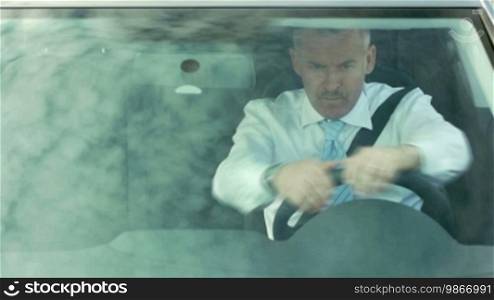 High angle view of Caucasian mid adult businessman with hands on steering wheel, looking away.