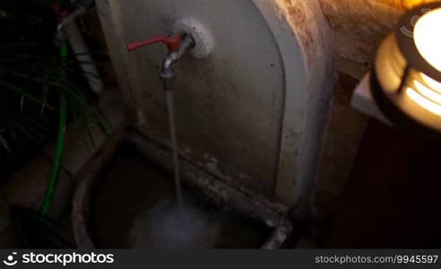 High angle view of father washing sand off his son's legs using a wall-mounted tap and fresh water illuminated by an uplighter