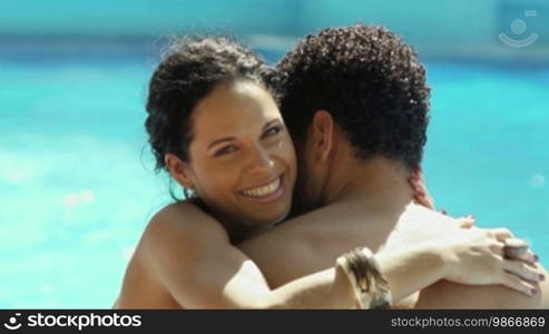 Honeymoon: happy young newlyweds hugging and relaxing near hotel pool