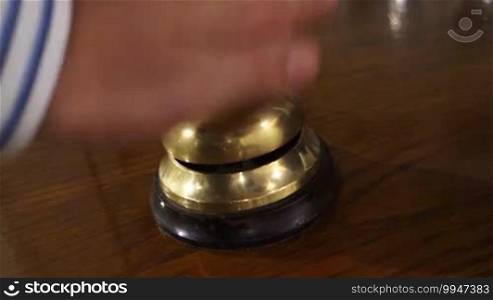 Impatient guest repeatedly presses the bell at the reception of a hotel but no service comes