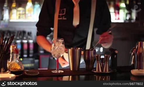 In a nightclub or pub, a professional bartender preparing a cocktail with ice, a mix of alcohol. The barman measures quantities for a perfect cocktail. Concept: disco, fun, friends, cocktail.