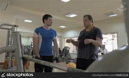 In the gym. Young trainer talking to a man and giving a piece of advice in workout